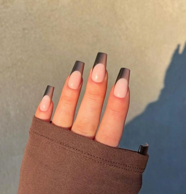 A closeup of a woman's fingernail with brown ombre for your French tips that has nude base color