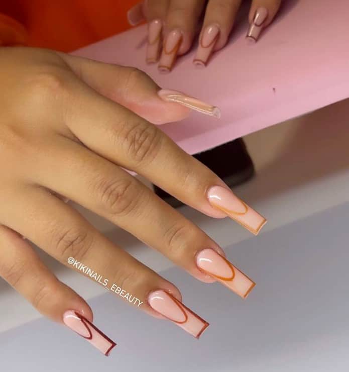 A closeup of a woman's fingernails with a glossy peach nail polish that have outlines in different shades of brown 