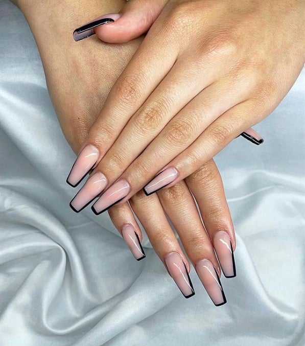 A woman's fingernails with nude nail polish base that has black polish outline