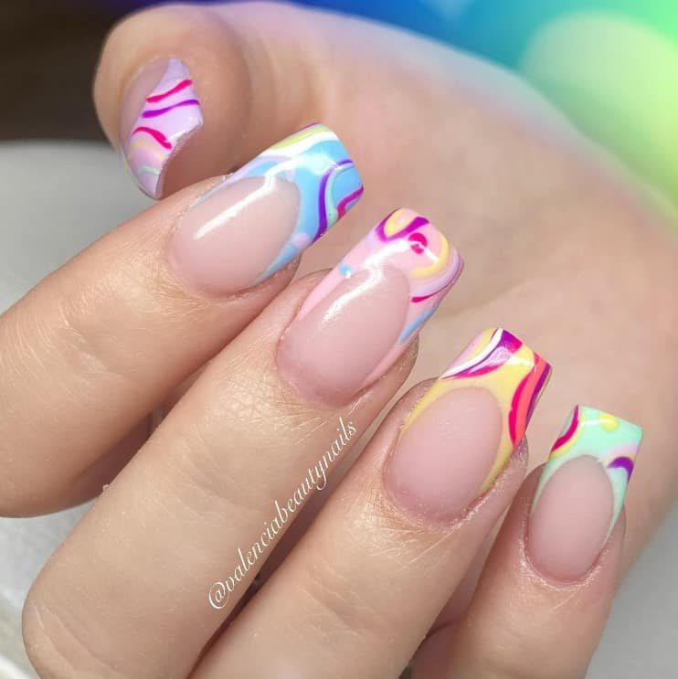 A closeup of a woman's fingernails with nude nail polish that has multicolored French tips with fun curved lines