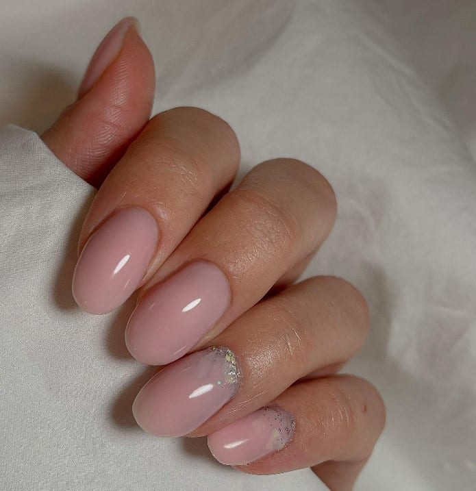 close up photo of woman's fingernails with pale pink nail polish and a touch of silver glitter