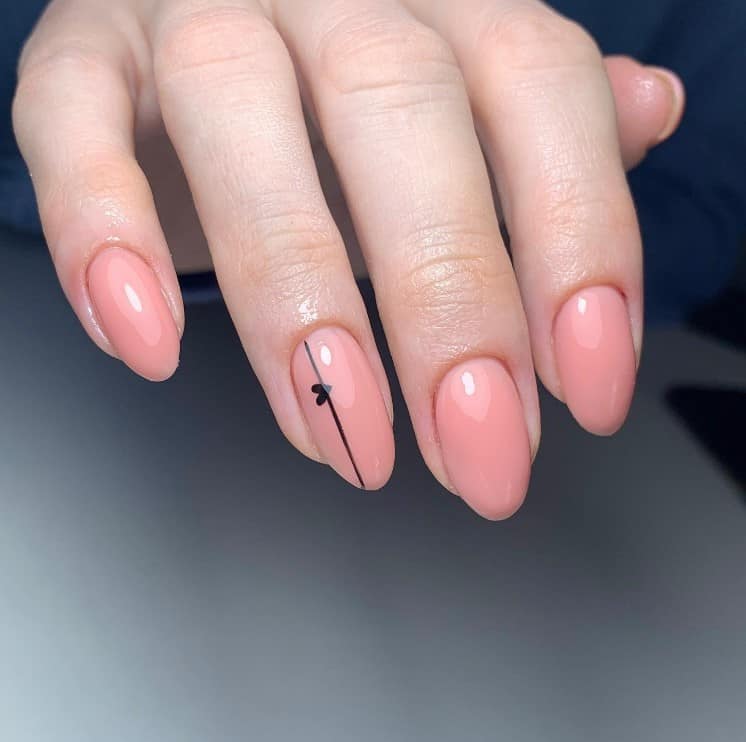 A closeup of a woman's fingernails with dark peach-color nails that has black vertical line piercing through a tiny black heart