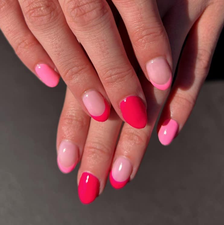 A closeup of a woman's fingernails with light, hot, and regular pink nail polish that has stunning clear nails with neon tips