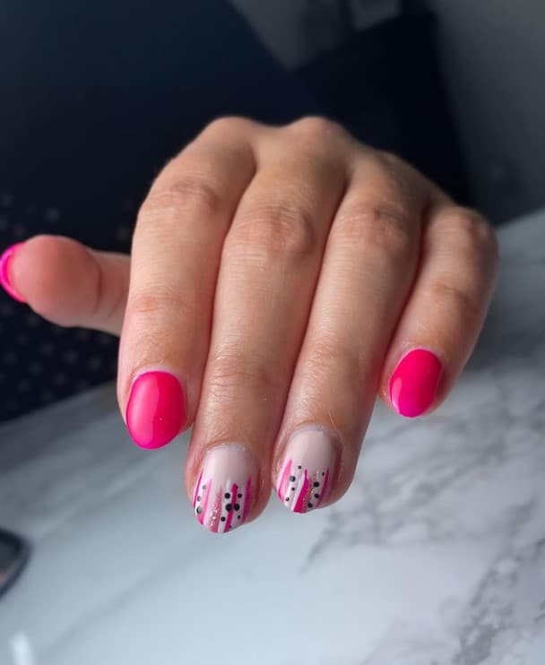 A woman's fingernails with neon and nude pink nail polish that has stripes and dots
