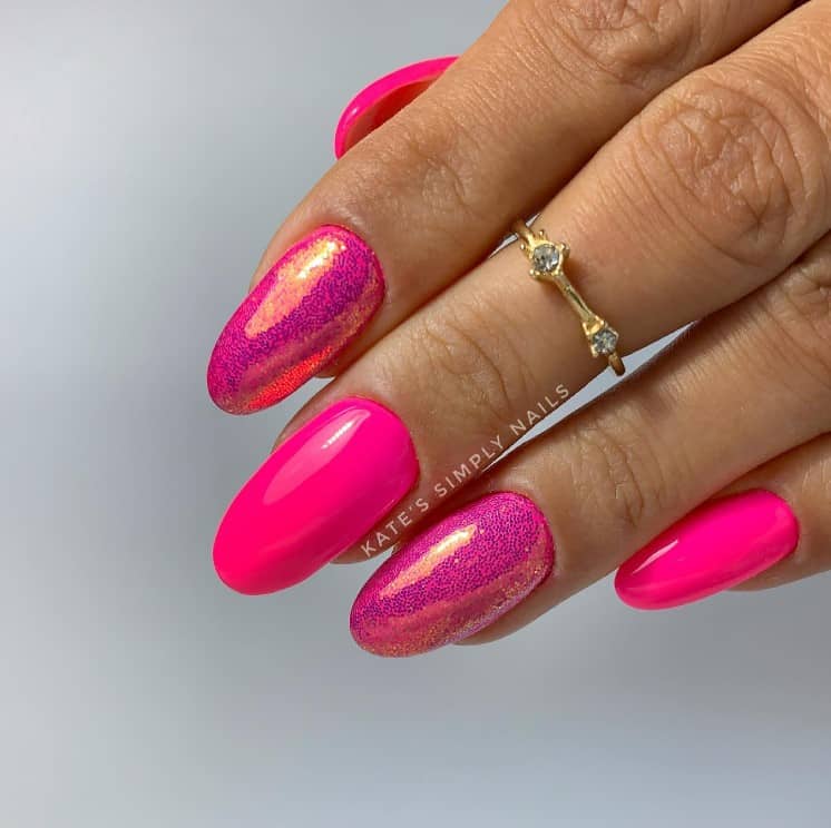 A closeup of a woman's fingernail with gorgeous neon pink nails that has chrome holographic polish and distinct holographic rainbow effect