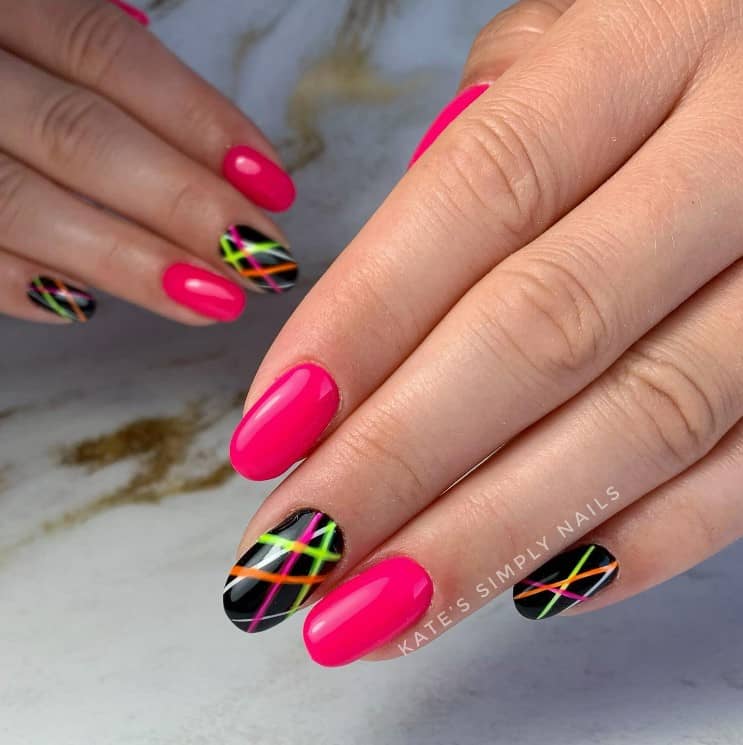A closeup of a woman's fingernails with neon pink nails and disco-inspired nail art that has neon pink nails with black accent nails and neon beams of light