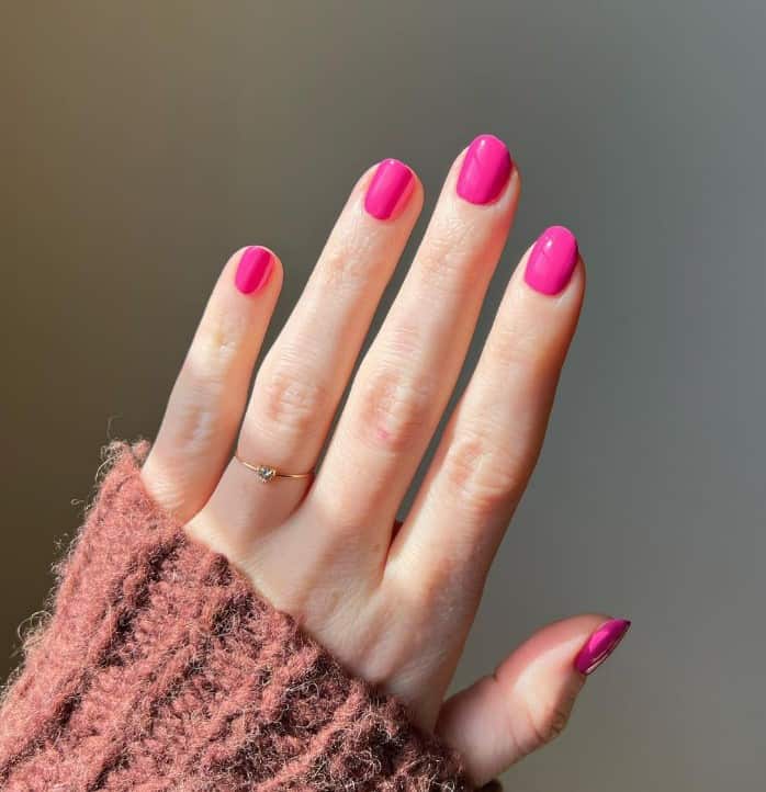 A closeup of a woman's fingernail with short squoval nails that say Barbie that has ultra feminine, neat, and classy manicure