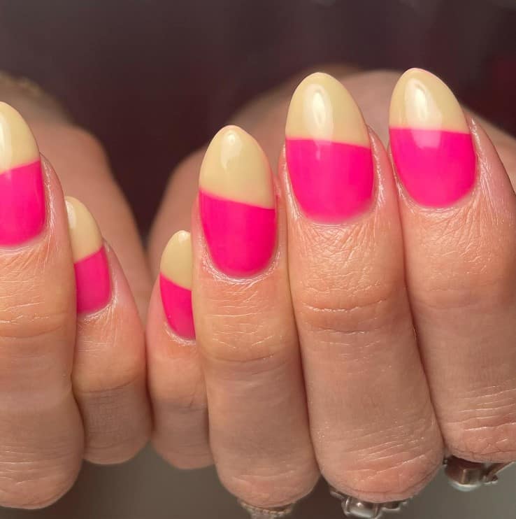 A closeup of a woman's fingernails with neon pink base nails that has flesh colored tips