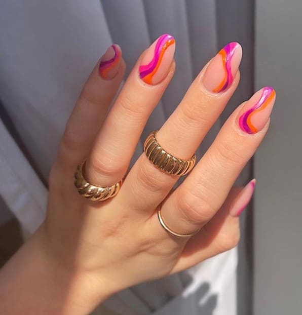 A woman's fingernails with a nude nail polish that has pink, white, and orange swirls