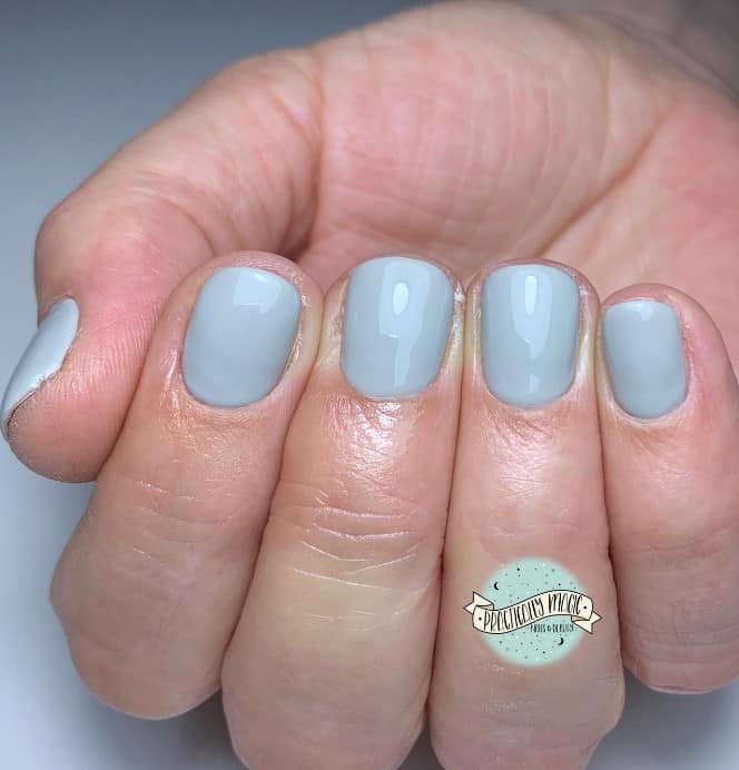close up photo of woman's fingernails with light gray nail polish