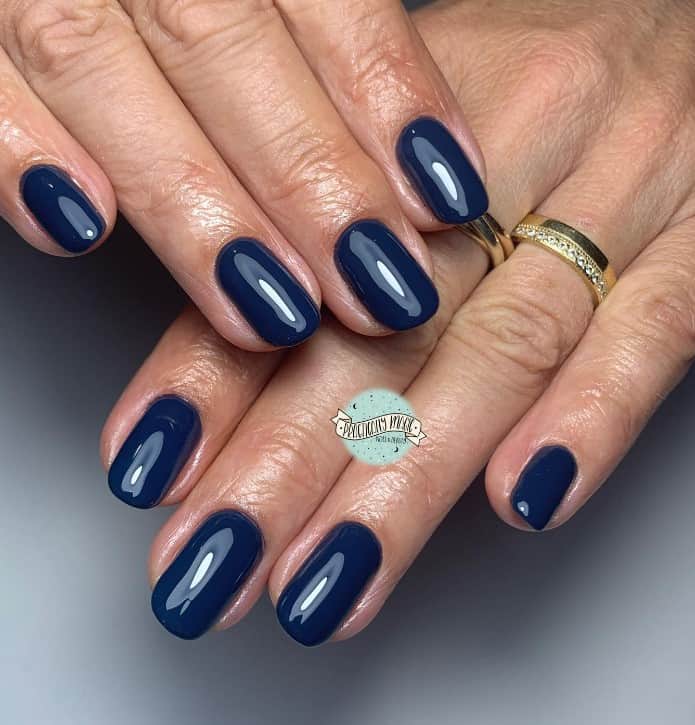 woman's fingernails with navy blue nail polish
