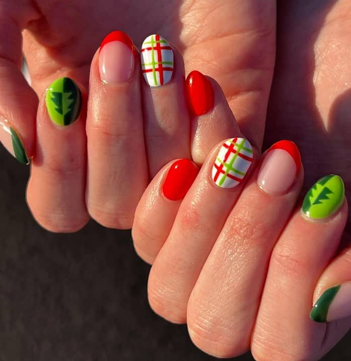 A closeup of a woman's fingernails with mix of green and red French tips, Christmas trees, and the green, red, and white stripes nail designs