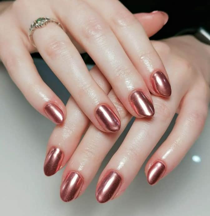 A closeup of a woman's fingernails with a glossy bronze-colored nail polish
