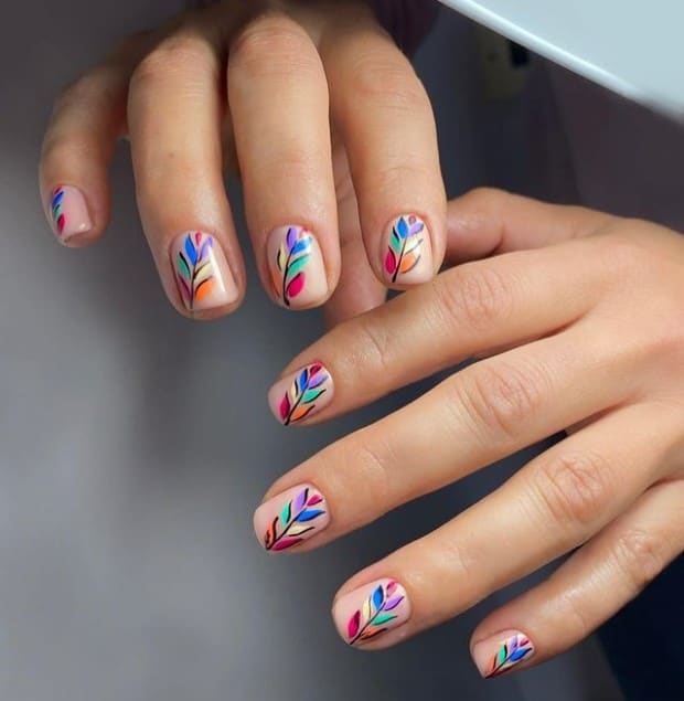 A woman's fingernails with a nude nail polish that has orange, aqua, blue, lavender, red, and white for the leaves while using
more traditional black lines for the stems
