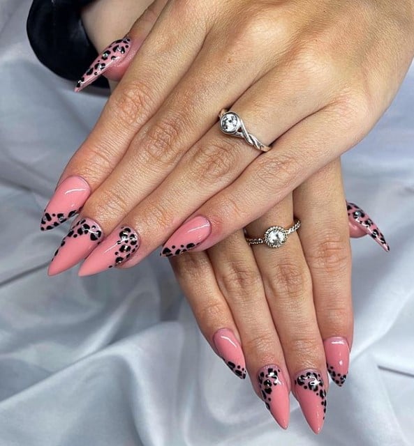 A closeup of a woman's fingernails with a pink nail polish that has leopard-print accents