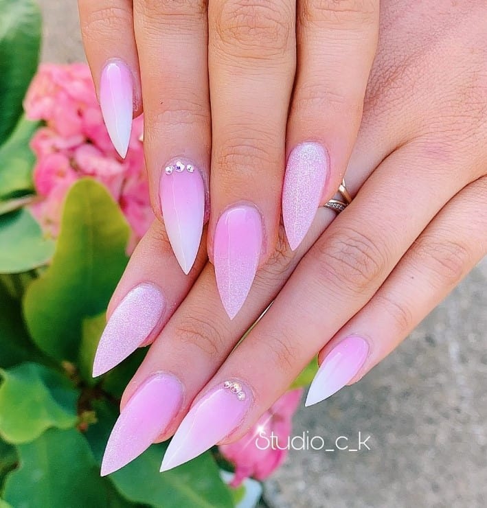 A closeup of a woman's short stiletto fingernails with pink-and-white ombré nails