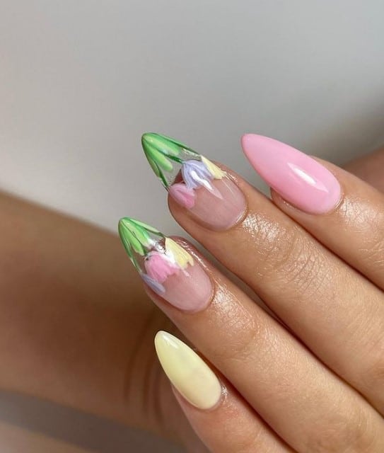 A woman's fingernails with a combination of
clear, pink and yellow nail polish that has tulip nail art on clear nails 