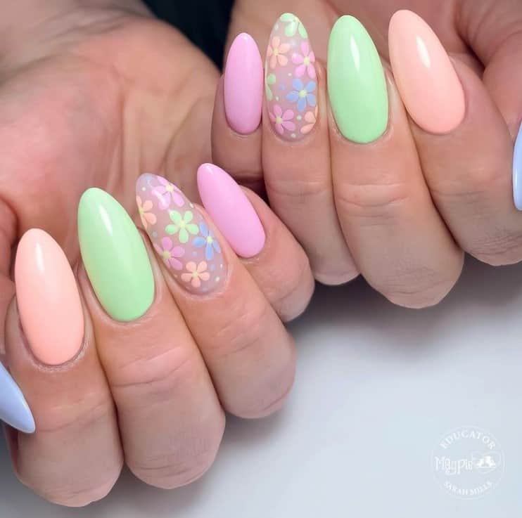 A closeup of a woman's fingernails with multicolored pastel nail colors that has floral accent nails