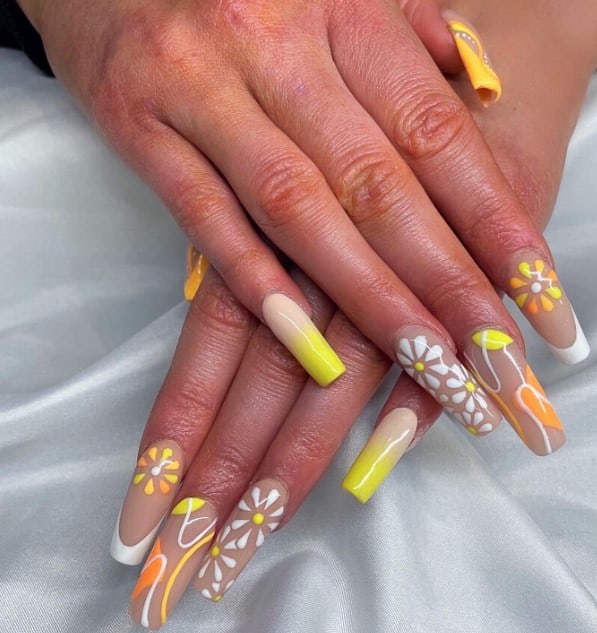 A closeup of a woman's chic light nude base fingernails with mesmerizing fusion of yellow, orange, and white hues that has daisy flowers, a seamless ombré, and thin swirls