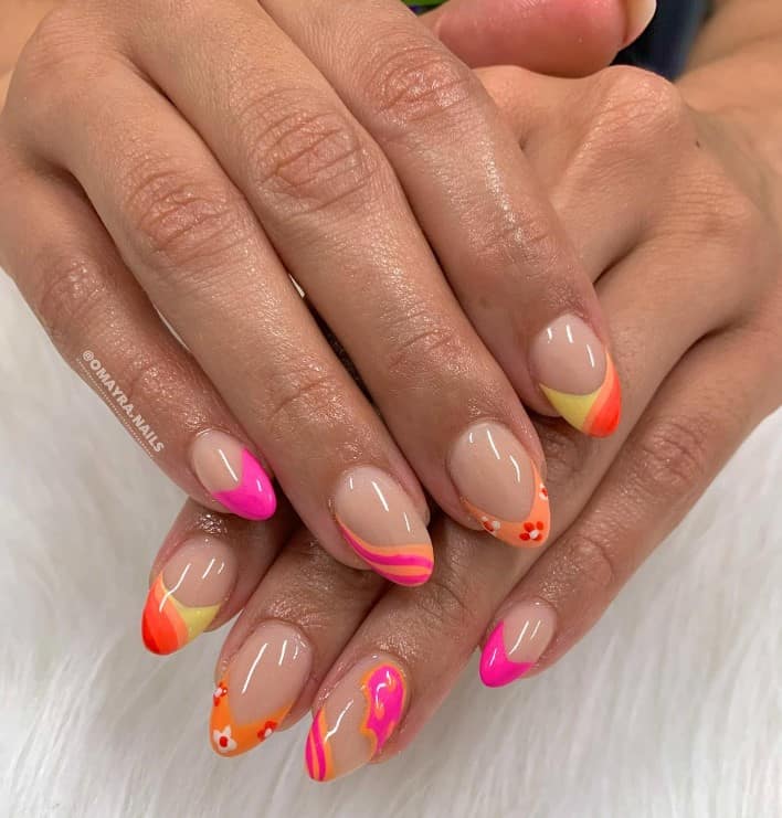 A closeup of a woman's fingernails with short almond-shaped nails that has playful swirls to dainty flowers and bold solid colors
