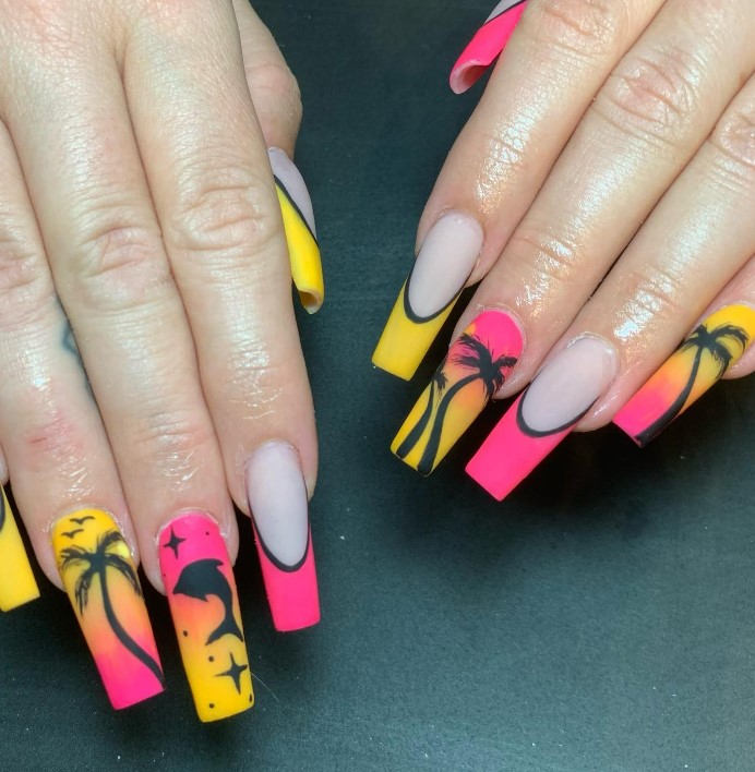 A woman's fingernails with a nude nail polish base that has playful palm tree and dolphin nail art in hues of pink and yellow