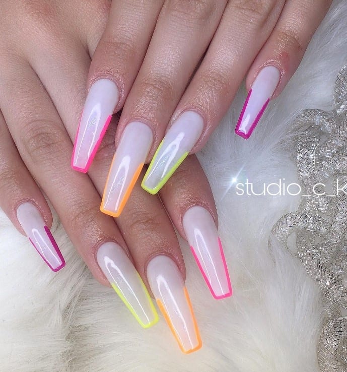 A closeup of a woman's fingernails with Long translucent white coffin nails that has bold neon colors in pink, orange, yellow green, and magenta