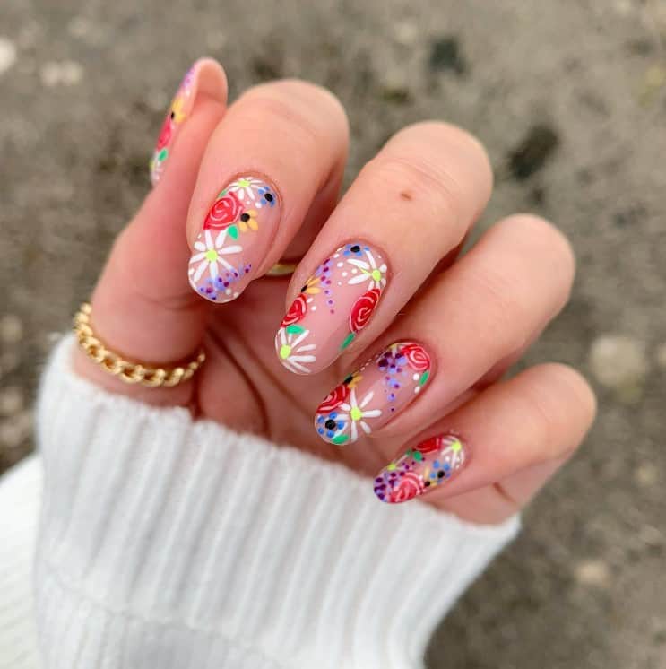 A closeup of a woman's fingernails with a glossy nude nail polish that has multicolored flowers