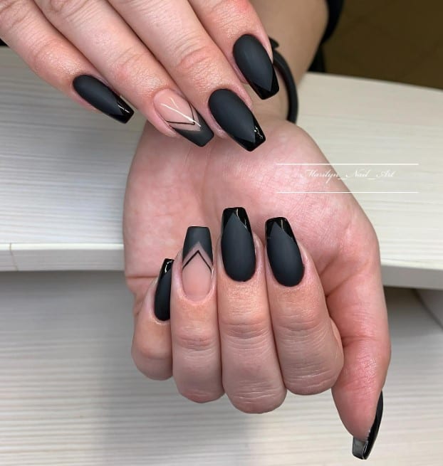 A woman's fingernails with a mix of nude and matte black nail polish base that has glossy black French tips paired with a nude black-tipped accent nail