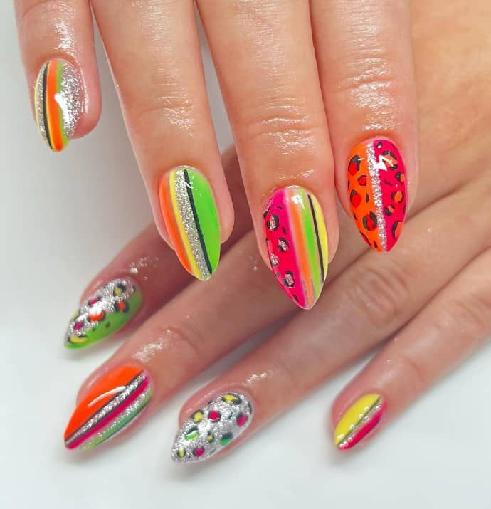 A woman's almond shaped nails with a mix and match of neon colors that has eye-catching vertical stripes and fierce leopard prints and silver glitter