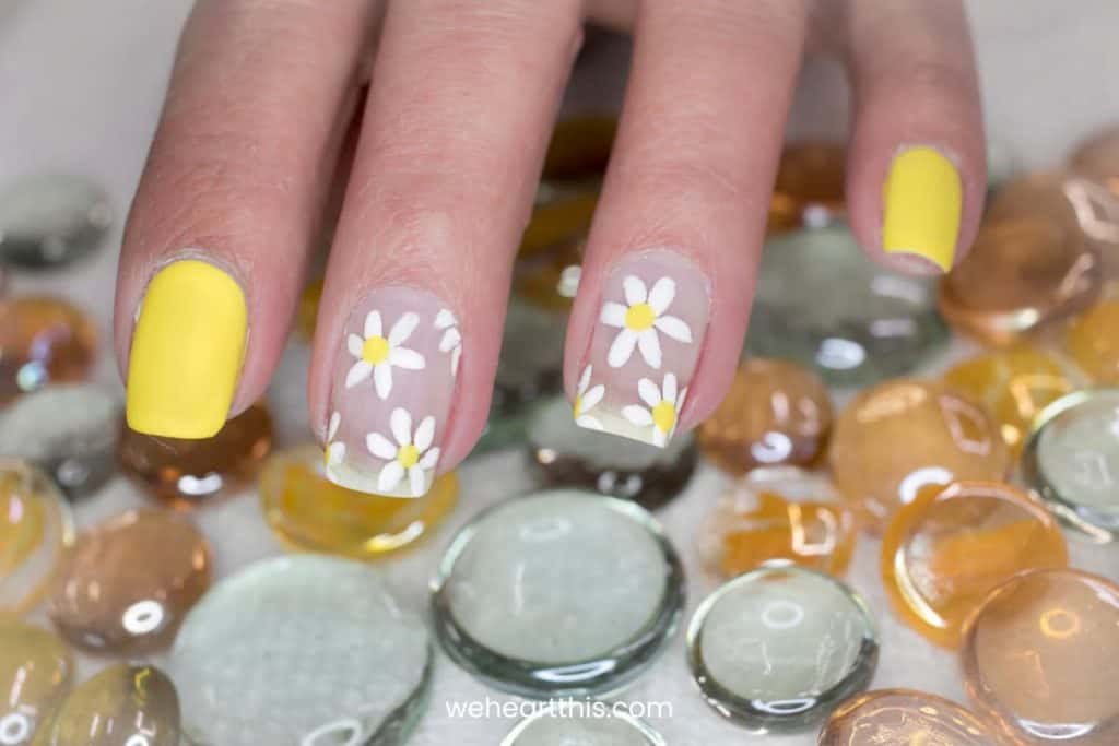 nails with yellow polished and daisy accent on other nails