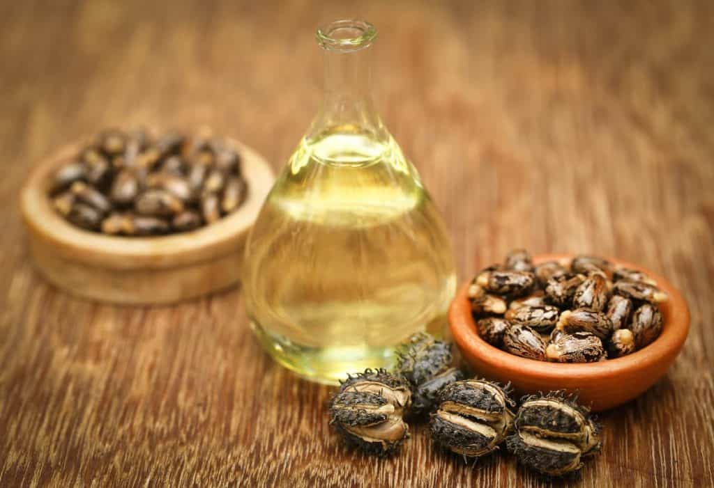 A bottle of castor oil and castor seeds wooden table.