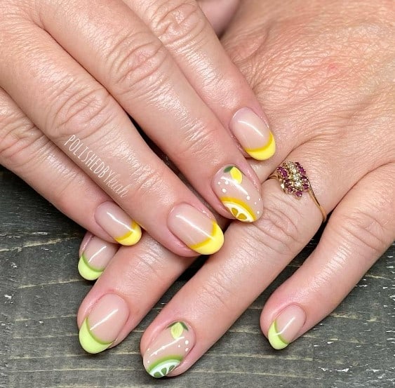 A closeup of a woman's fingernails with a nude nail polish base that has French tips coated in two intoxicating shades of bright lemon yellow and lime green, lemon designs and white polka dots