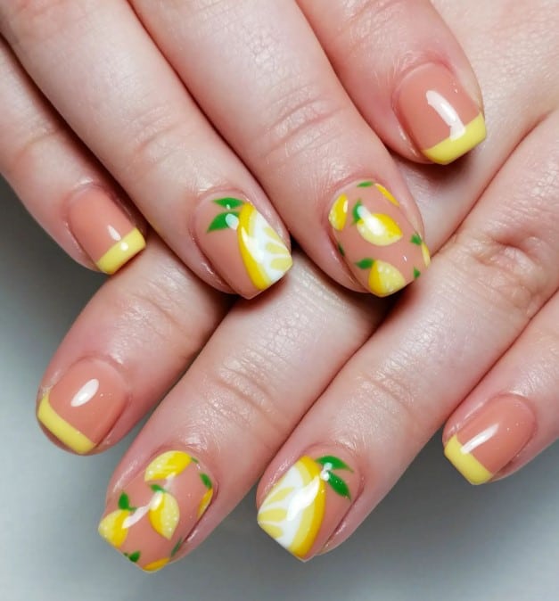 A closeup of a woman's fingernails with a dark peach nails that has sunny yellow tips and ripe lemon nail designs