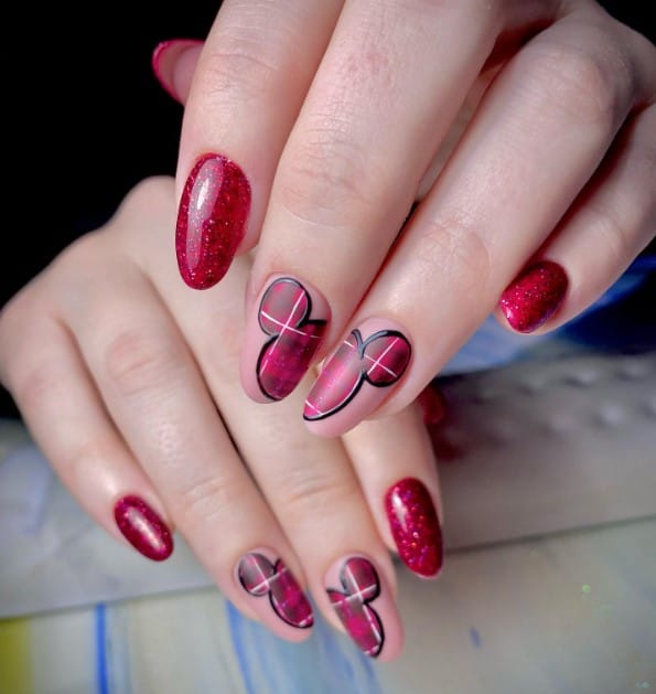 A closeup of a woman's fingernails with glittery red nails and nude nails that has Mickey Mouse silhouettes designed with red plaid and black outlines