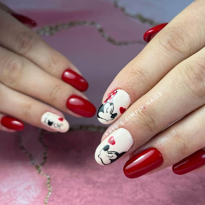 A woman's fingernails with white and red nail polish base that has Mickey Mouse and Minnie Mouse blowing kisses to each other nail art