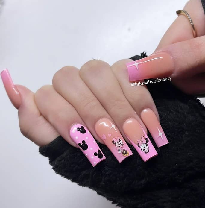 A woman's fingernails with beige acrylics that has light pink French tips. Minnie Mouse stickers, polka dots and Mickey silhouettes