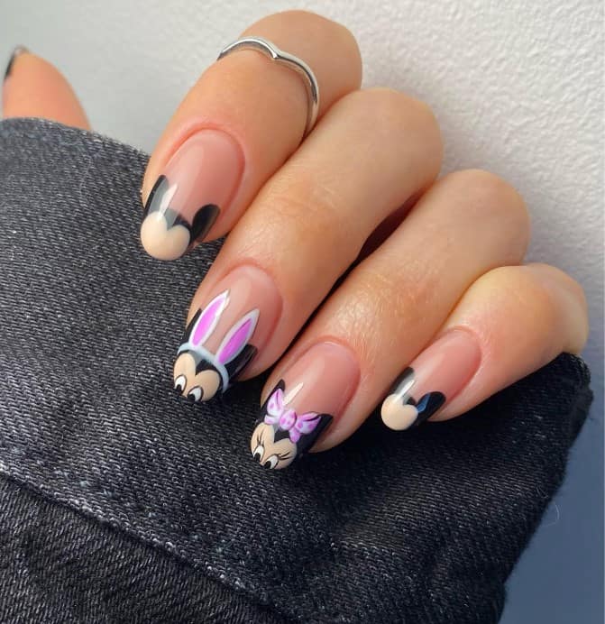 A closeup of a woman's fingernails with playful Minnie and Mickey Mouse French tips that has a nude backdrop