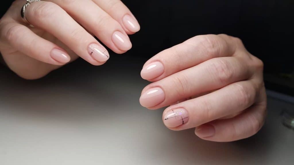 A woman's hands with a nude glossy manicure on her short nails