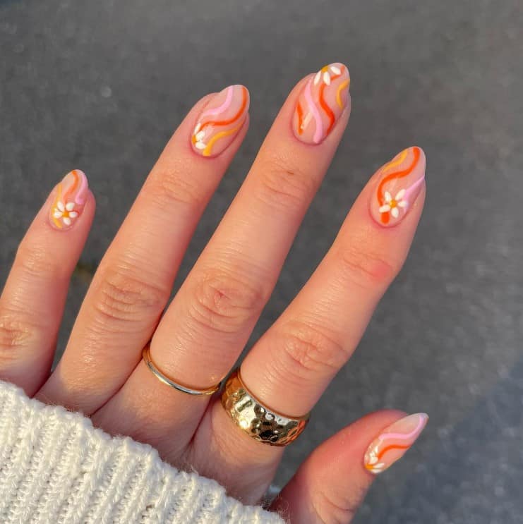 A woman's nails with nude nail polish base that has pink and yellow summer swirls with white peek-a-boo daisies nail designs