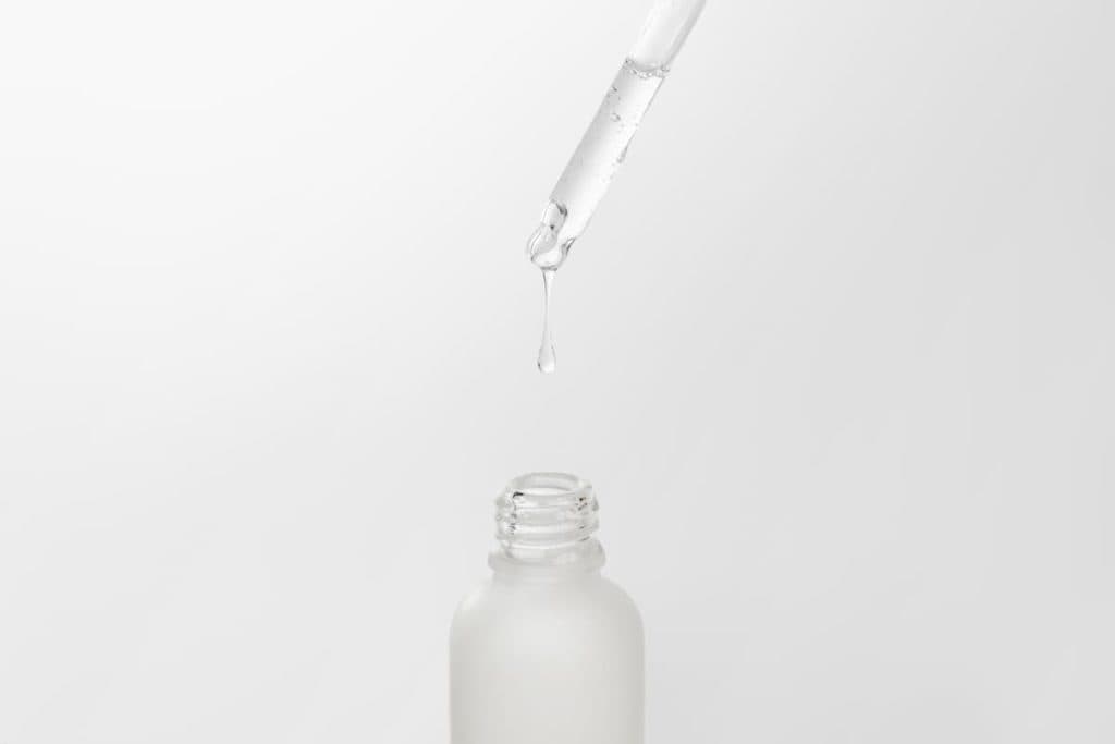 A white bottle with a drop of liquid coming out of it.