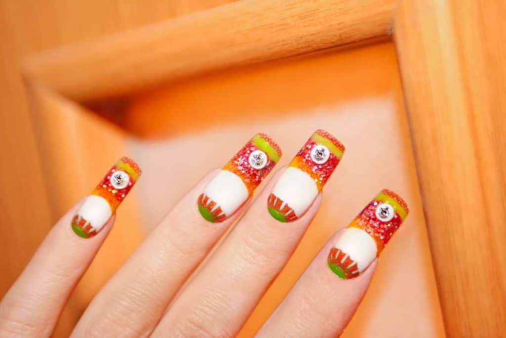 A woman's nails are decorated with colorful acrylic designs with white base.