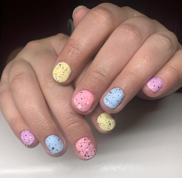 A woman's hands with short round nails look like actual Easter eggs with pastel colors and white and black dots