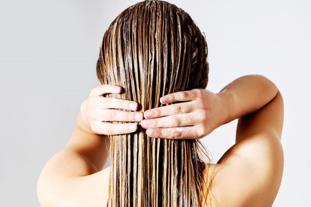 A woman's hands touching her hair with keratin treatment