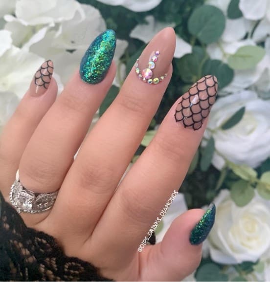 This design features nude nails decorated with black scales and 3D rhinestones
