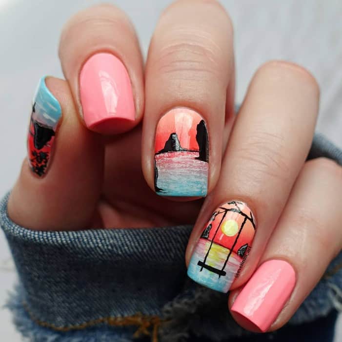 this design pairs pale pink nails with nail art that features pink skies, blue waters, black cliffs and stones, and a black swing