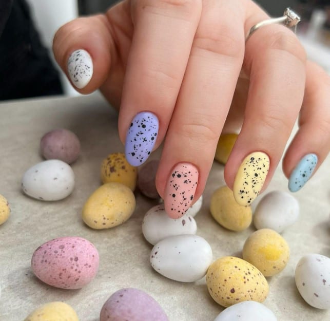 A woman's hand with pastel colorful easter eggs on it.