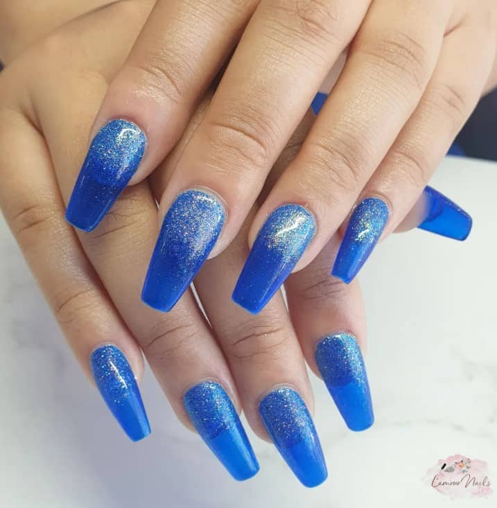 A woman's nails with glitter ombre with translucent blue nail polish