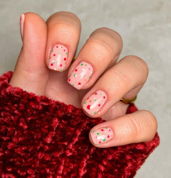 A woman's hand holding a pink and white polka dot nail polish.