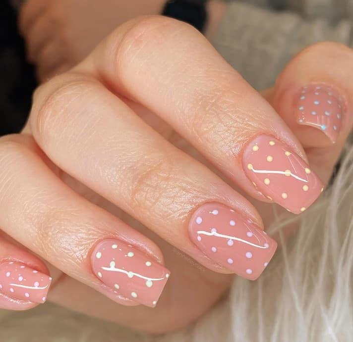 A woman's nude nails with cute polka dot nail design