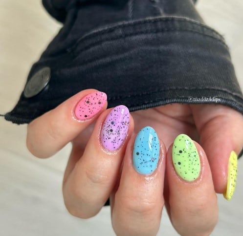 A woman's hand speckled egg nail design boasts pastel colors and a glossy finish